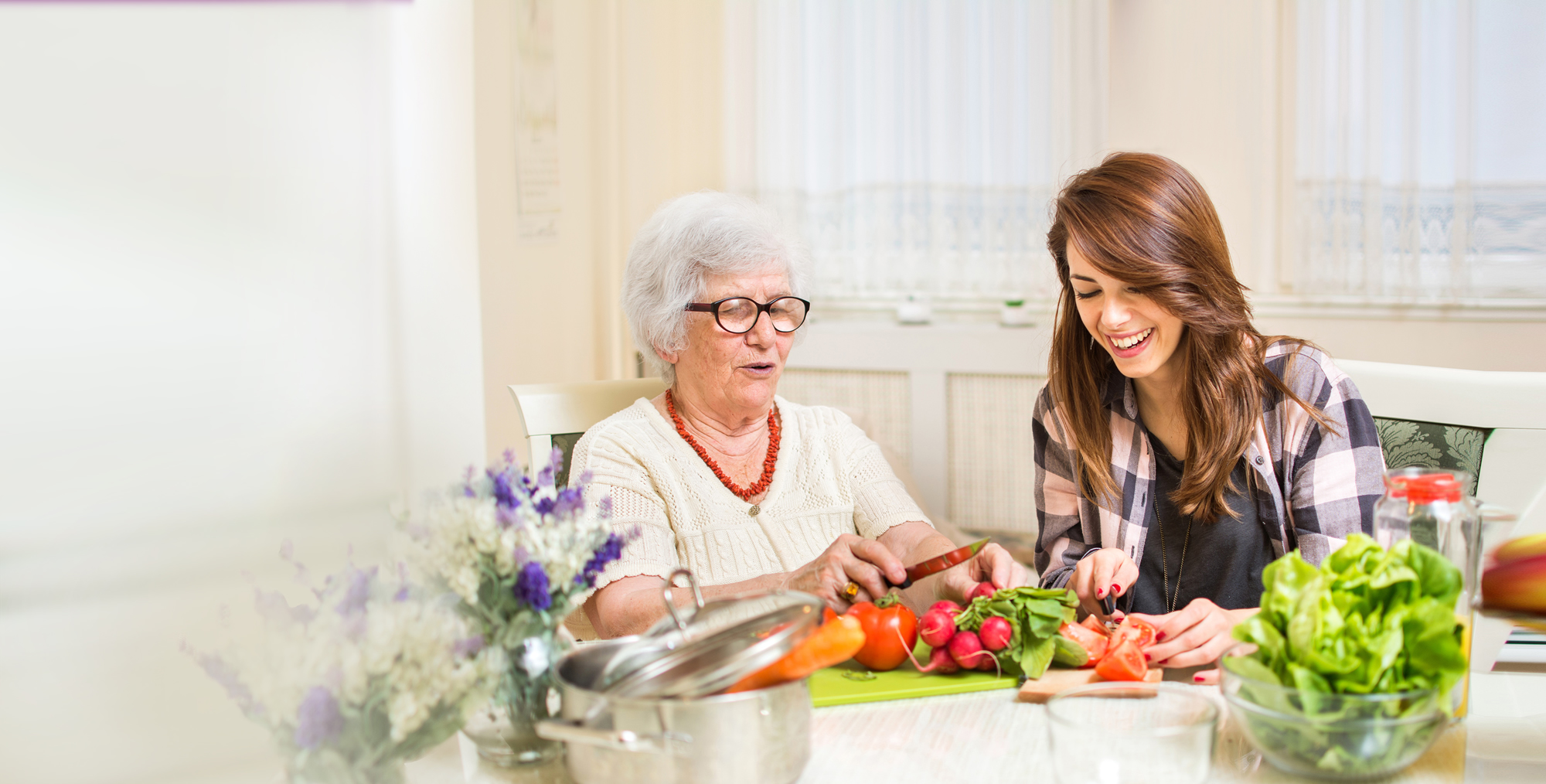 Elderly woman and young woman slicing vegetables
